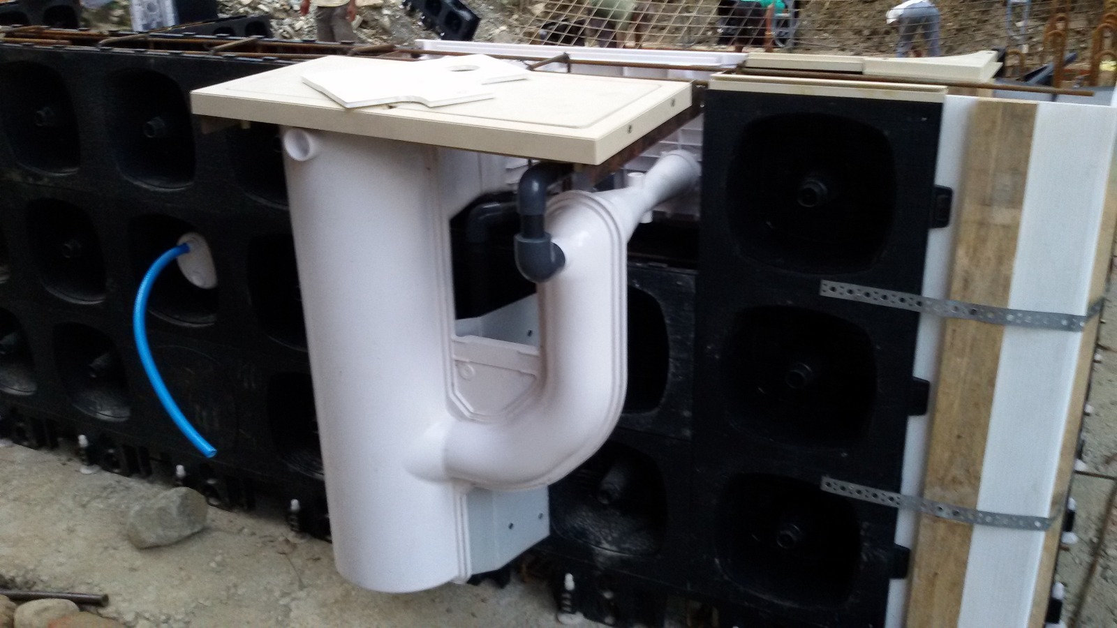 Pool construction stage 3: a skimmer body and connecting pipe fitted into the pool wall panels.