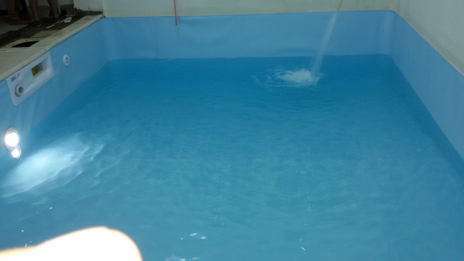 Indoor blue rehabilitation pool at Spinal Injury Rehabilitation Centre for Nepal, with underwater lighting and water being added.
